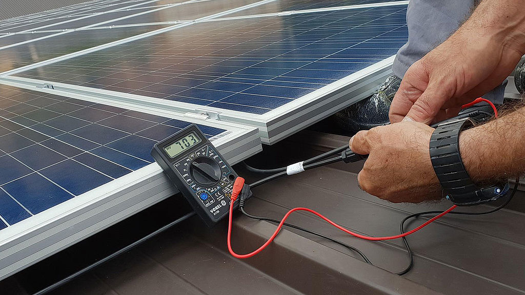 Arbeiter am Dach prüft eine Photovoltaikplatte