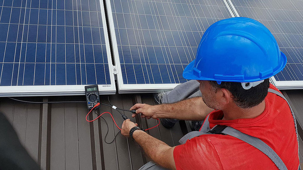 Arbeiter montiert Photovoltaikplatten am Dach